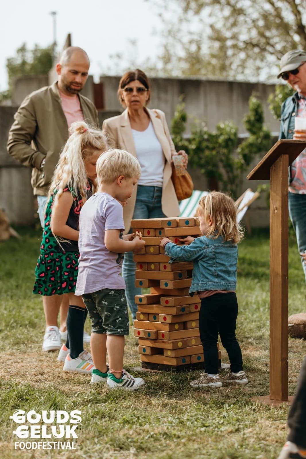 Kinderen bouwen samen aan de vallende toren, ouders kijken mee