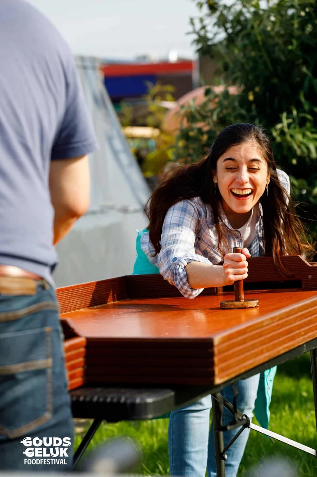 Lachend meisje aan een houten behendigheidsspel op een foodfestival