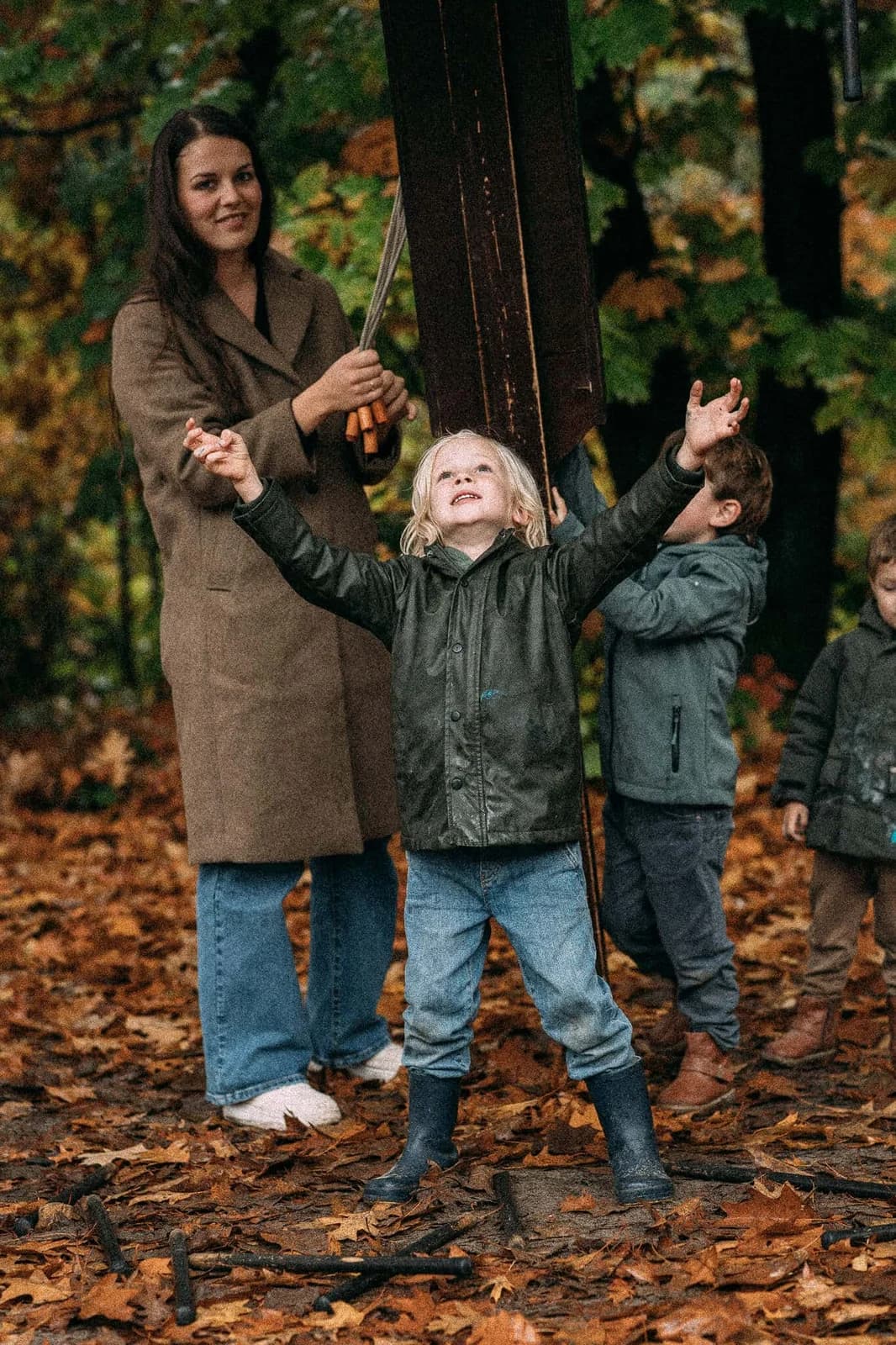 Moeder en kinderen juichen tussen de herfstbladeren op een evenement