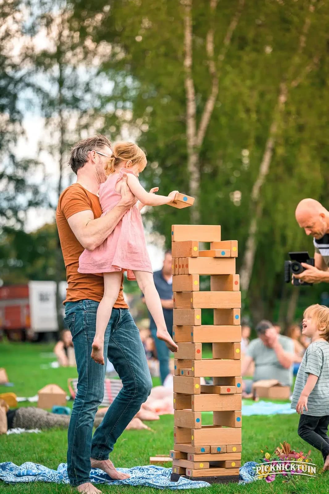 Vader tilt zijn dochter op bij de vallende toren op een festivalveld